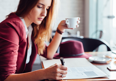 Woman editing manuscript for the appraisal journal while drinking coffee